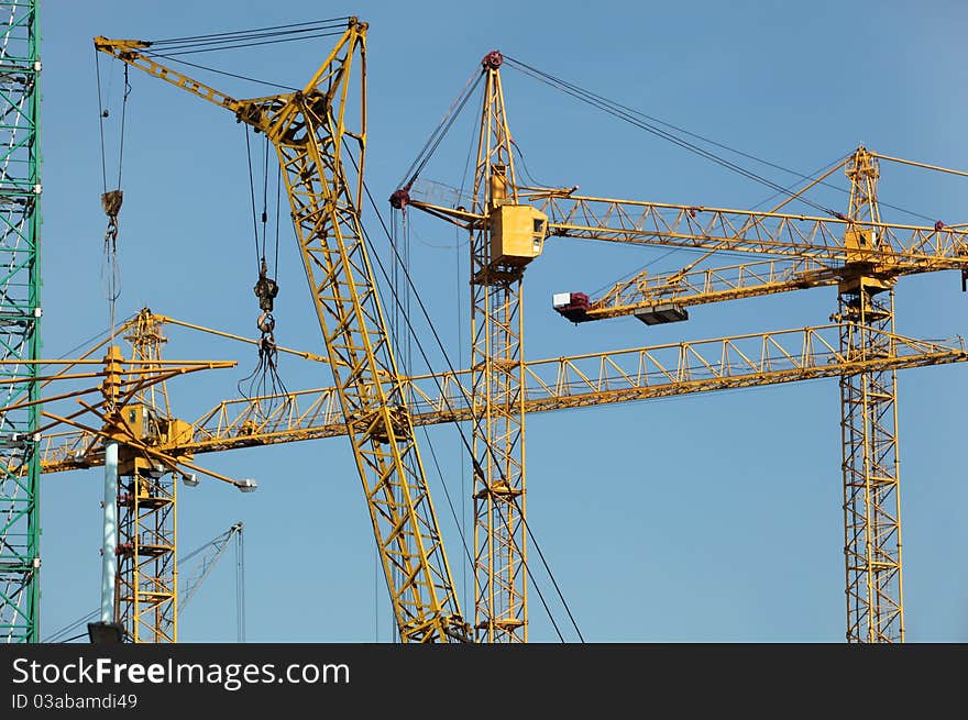 Six construction cranes over blue sky