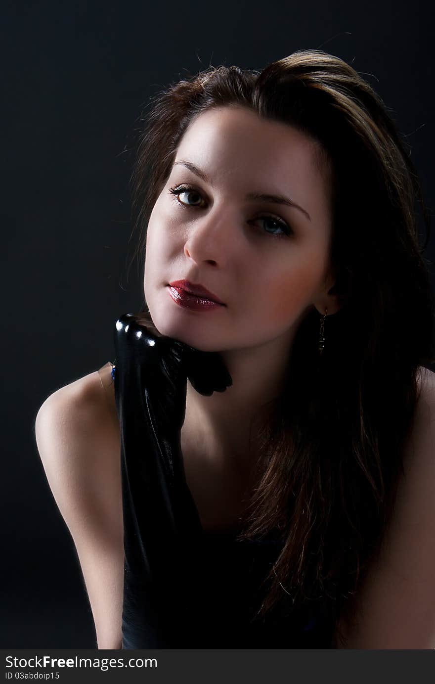 Portrait of young beauty woman in black gloves posing on black background in studio