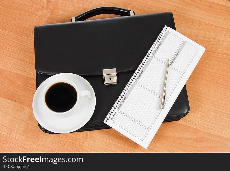 Black portfolio and coffee on a table still life