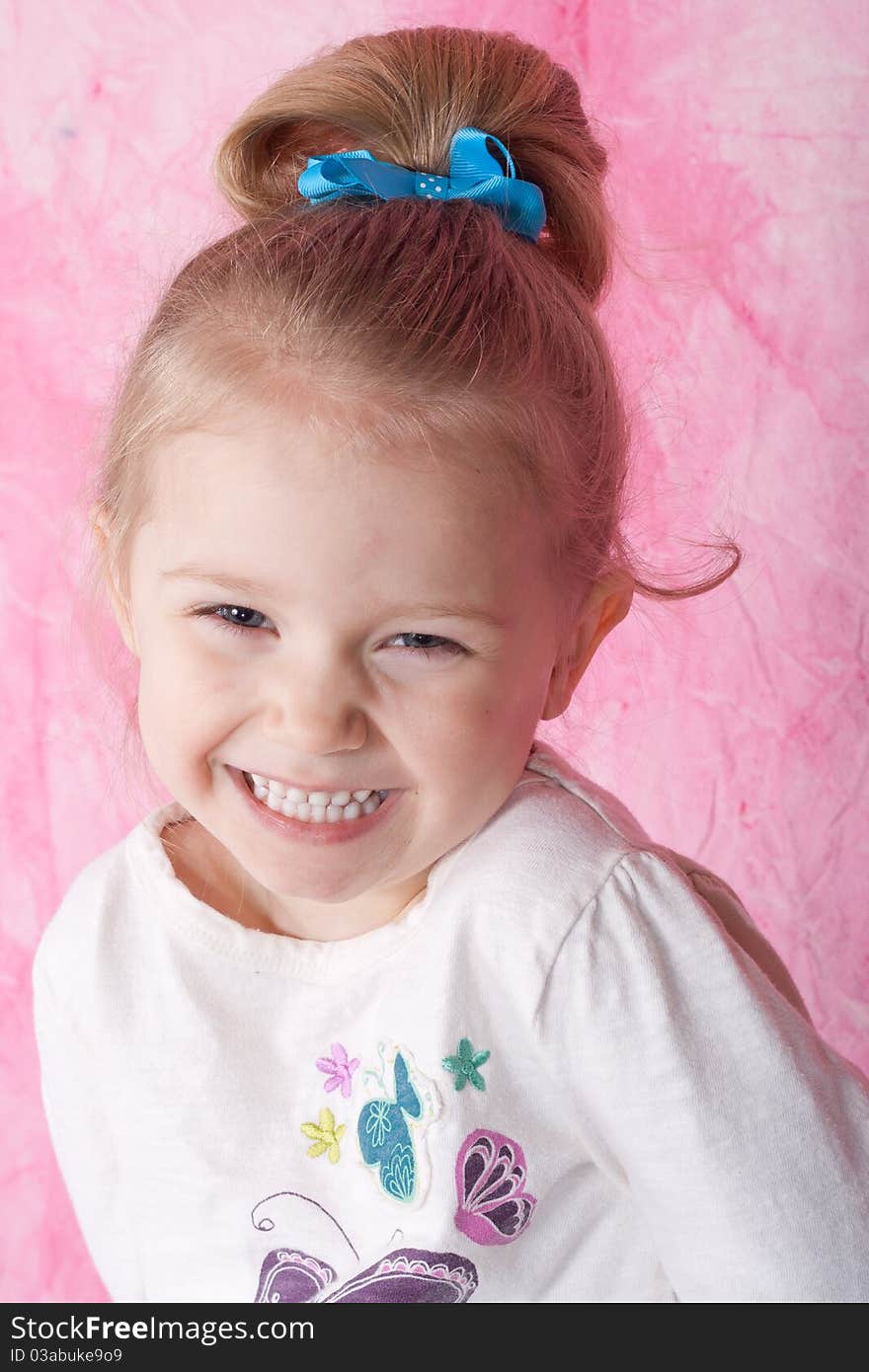 A happy but slightly shy young women. There is a pink background and she has a blue ribbon in her background. A happy but slightly shy young women. There is a pink background and she has a blue ribbon in her background.