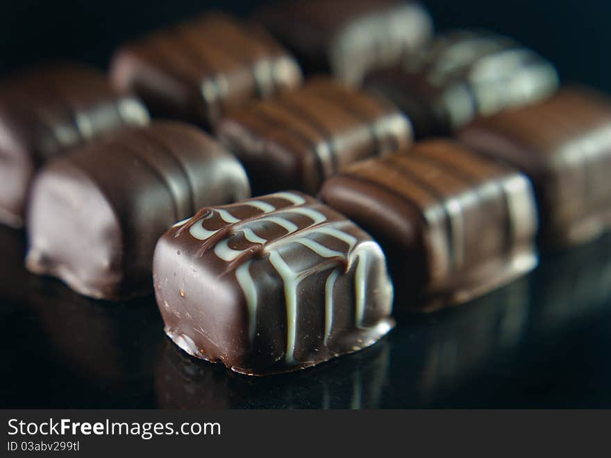 Delicious chocolates on a reflective background. The nearest one is in sharp focus.