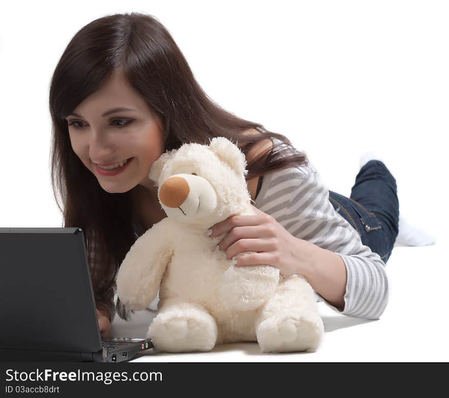 The beautiful girl embracing a teddy bear, communicates with notebook in a social network. The beautiful girl embracing a teddy bear, communicates with notebook in a social network.