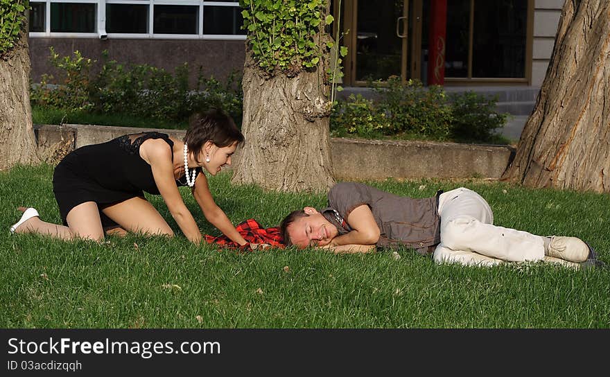 The guy and the girl have a rest in park on a grass. The guy and the girl have a rest in park on a grass