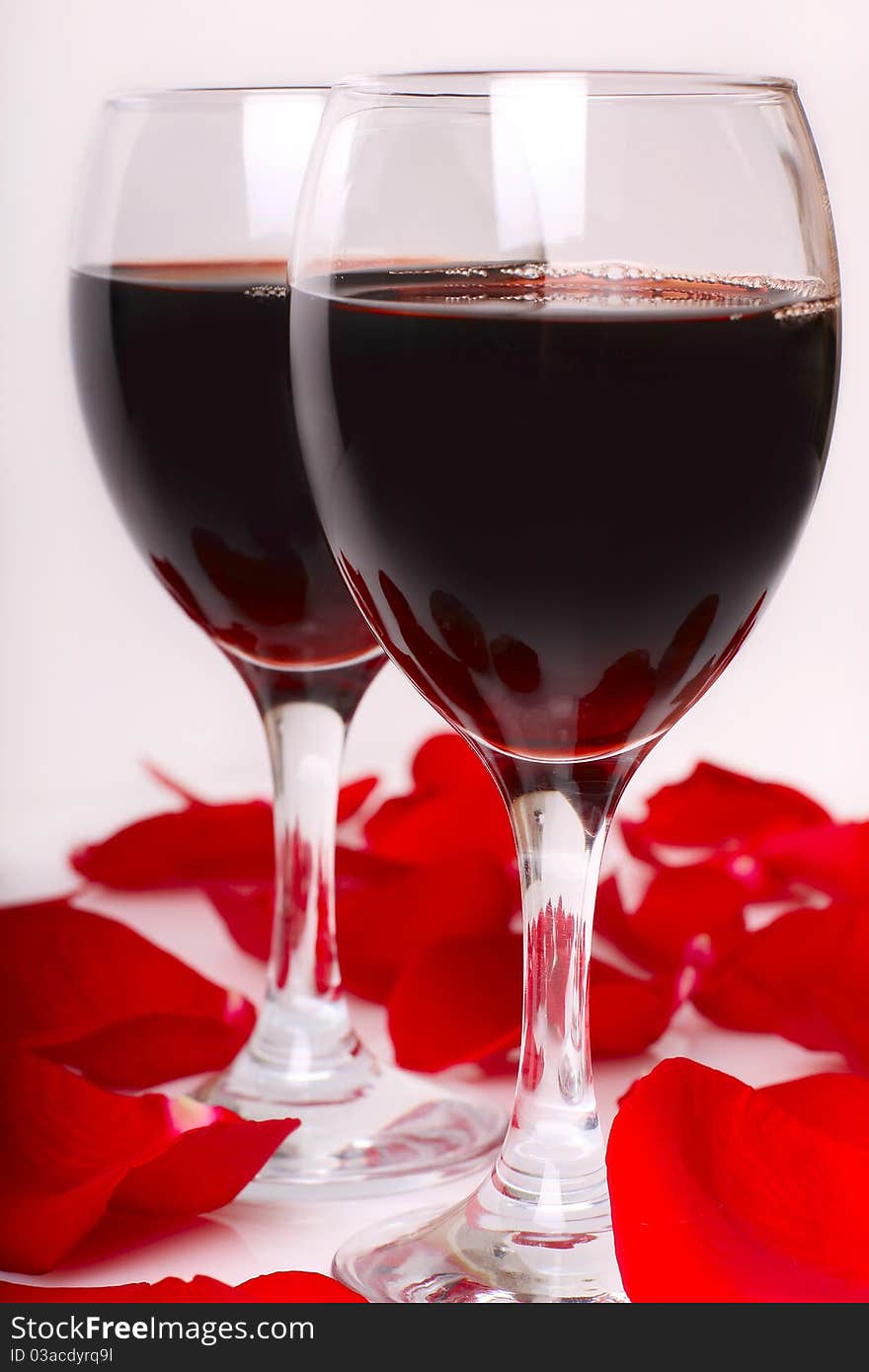 Two Glasses Of Wine With Petals Of Rose