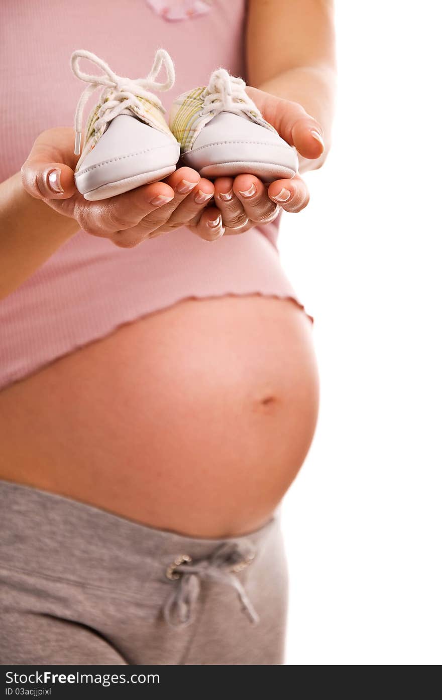 Pregnant woman holding pair of white shoes for baby (Shallow dof). Pregnant woman holding pair of white shoes for baby (Shallow dof)