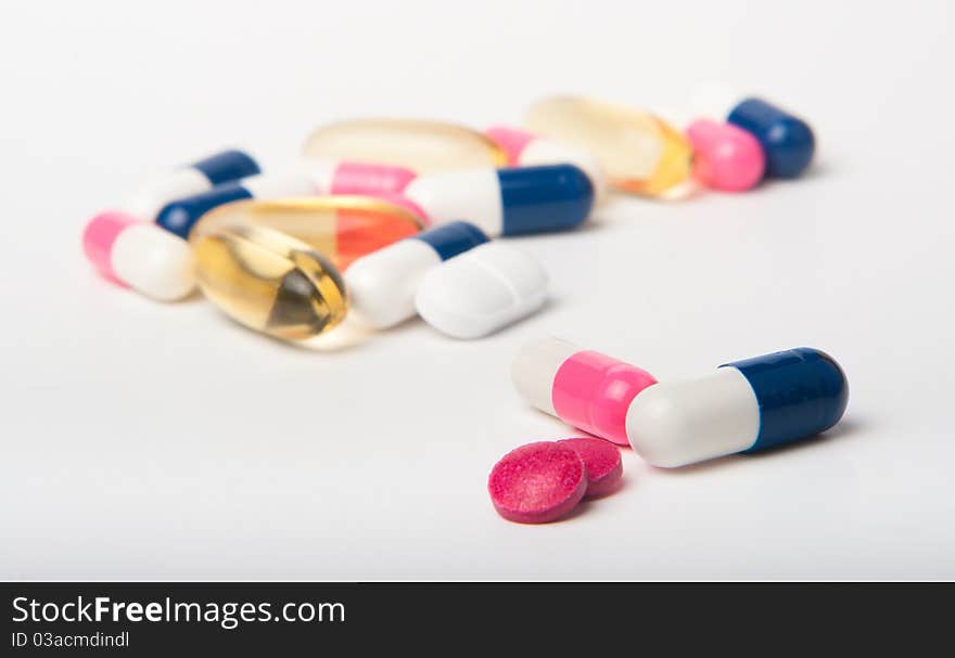 Macro of colored pills on white. Shallow focus on foreground capsules. Macro of colored pills on white. Shallow focus on foreground capsules.