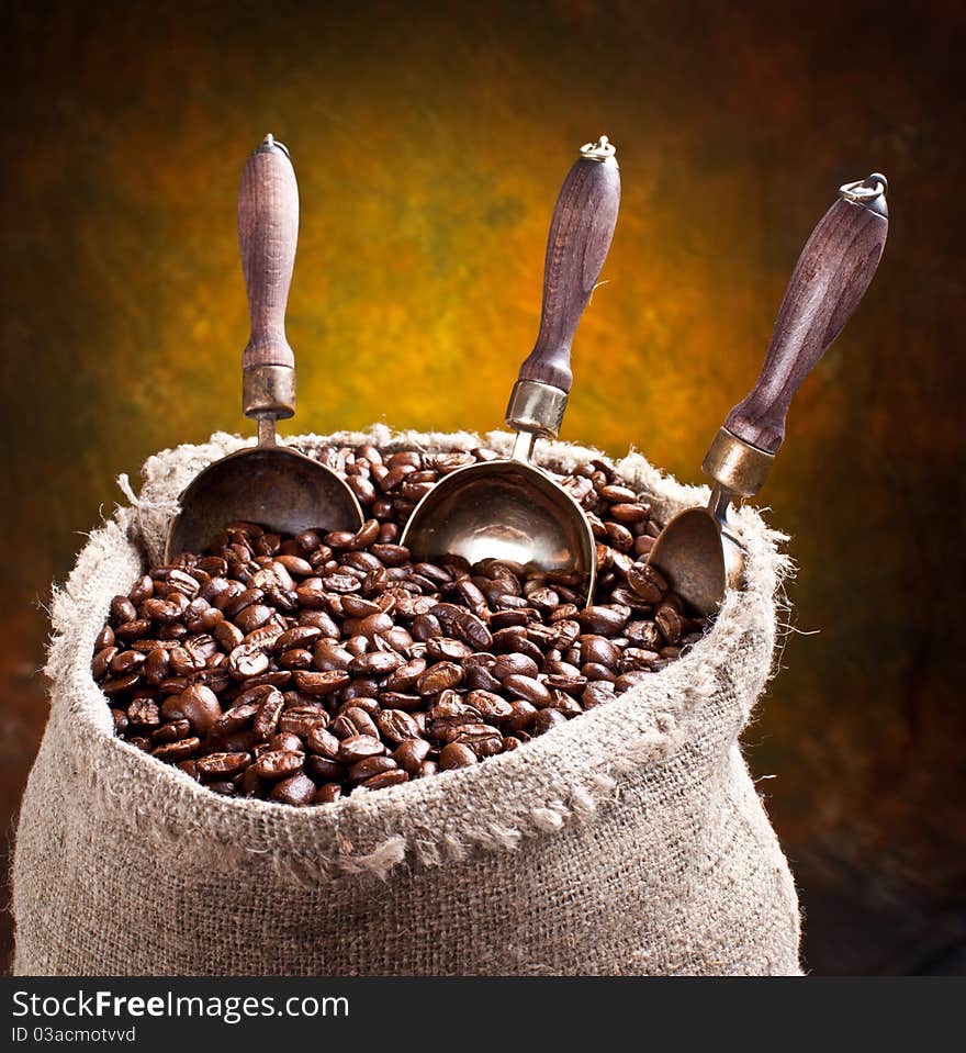 Sack of coffee beans and scoop. On a dark background.