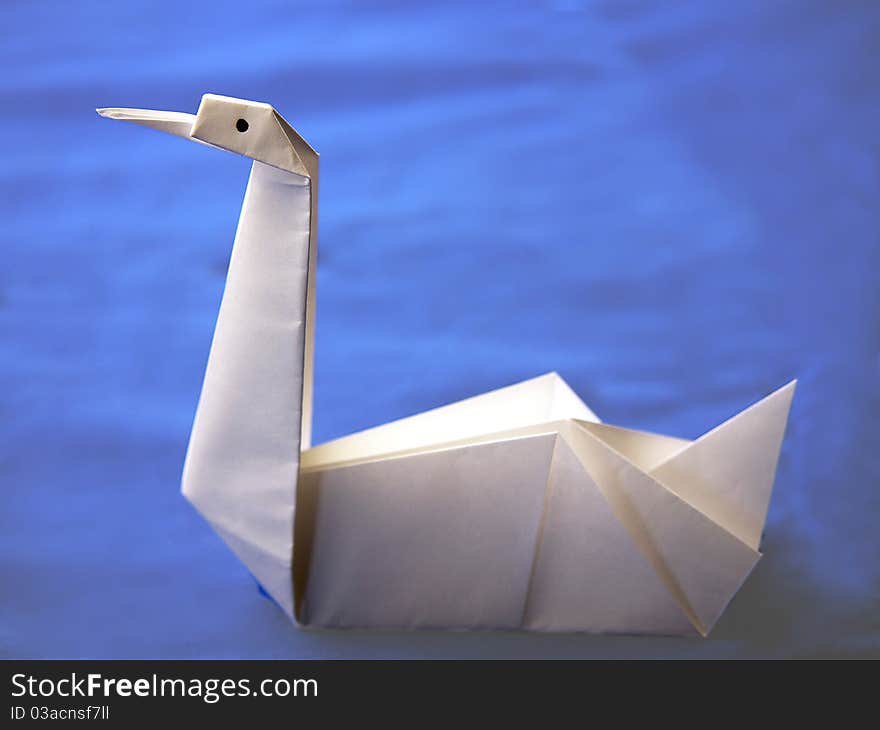 Origami white swan, made of white paper with black eyes. Origami white swan, made of white paper with black eyes