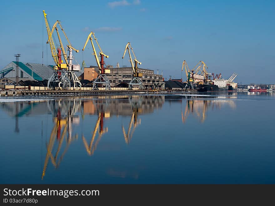 Harbor in sunshine winter day with crane reflection on water