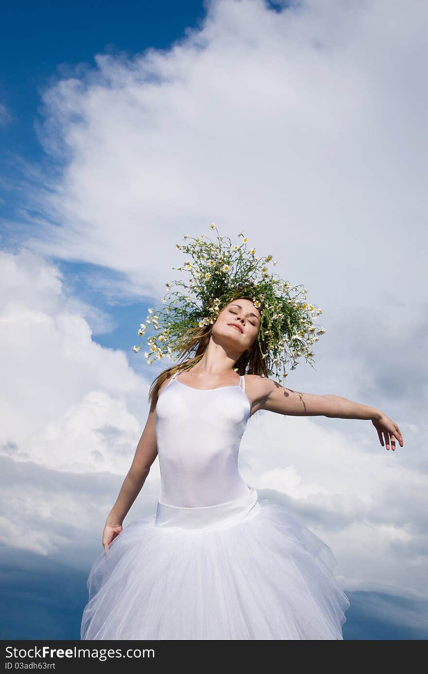 Young beautiful ballet dancer against cloudy sky