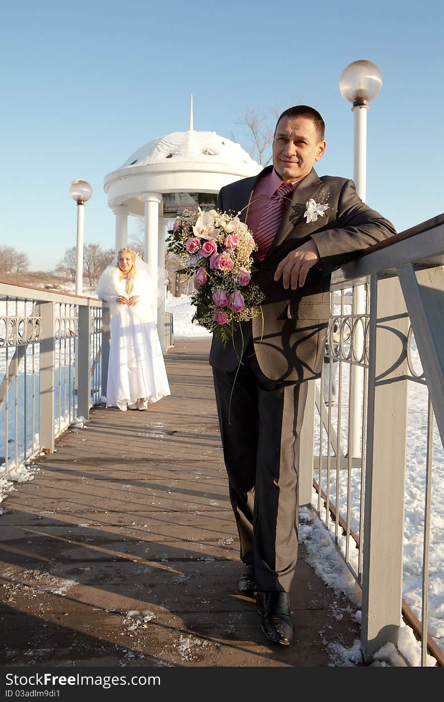 Colorful wedding shot of bride and groom standing on the bridge