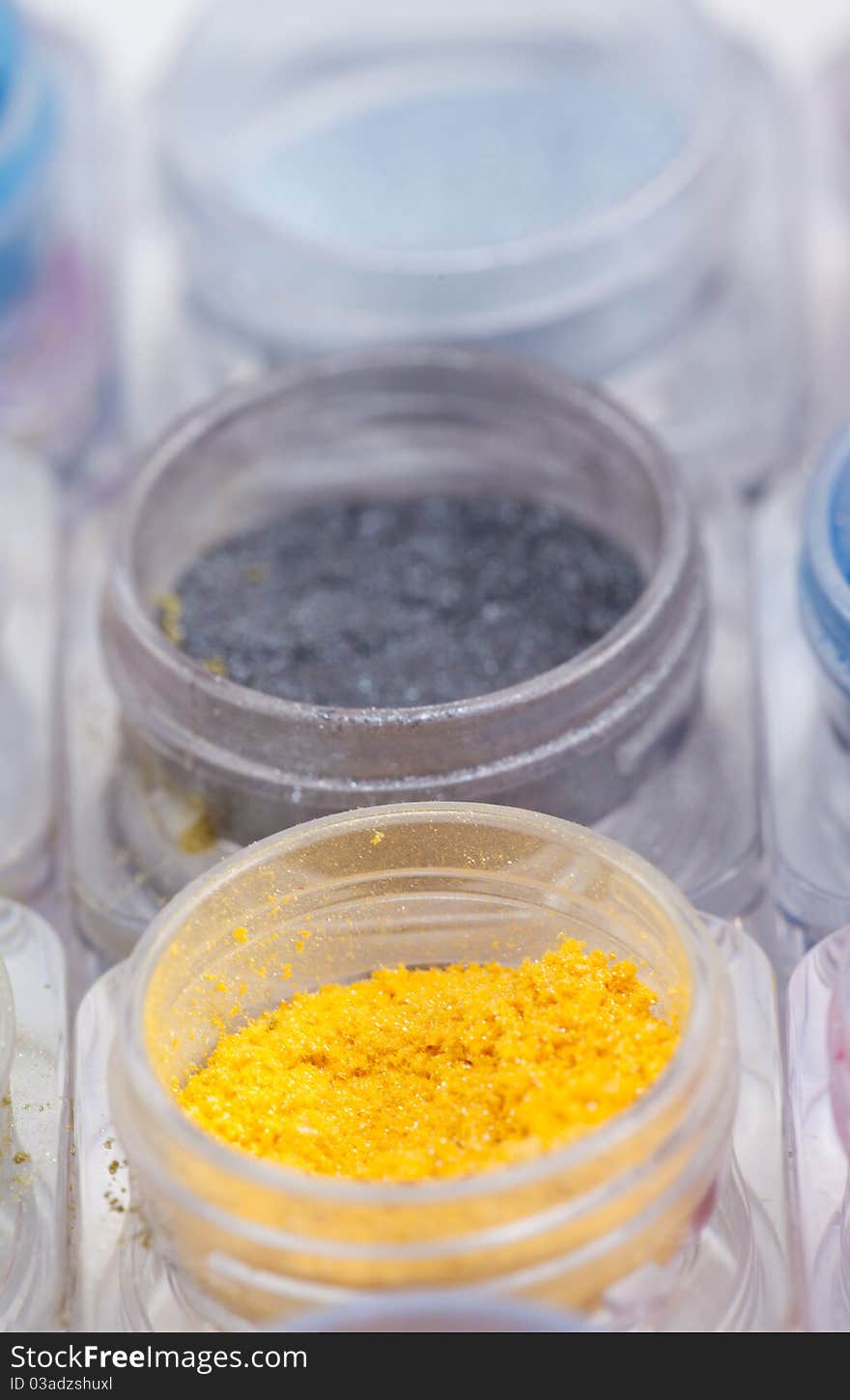 A close-up image of colorful cosmetic pigments placed in small containers. A close-up image of colorful cosmetic pigments placed in small containers