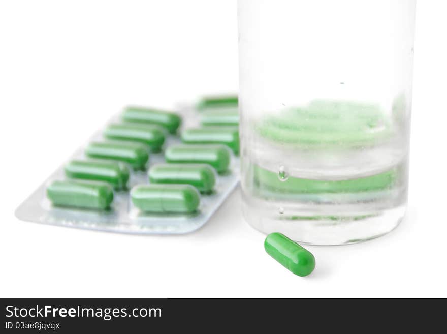 Green medical capsules and a glass of water isolated on white. Green medical capsules and a glass of water isolated on white