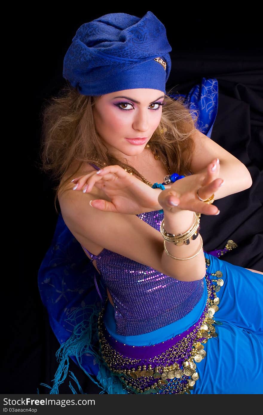 Beautiful girl in a turban and a stylized ethnic costume sits on headscarves