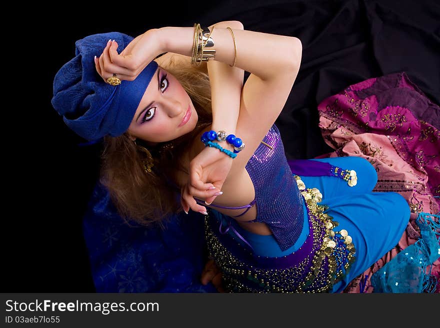 Beautiful girl in a turban and a stylized ethnic costume sits on headscarves