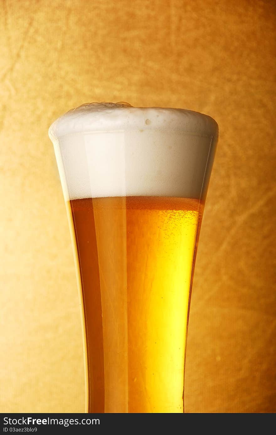 Glass of beer close-up over yellow background