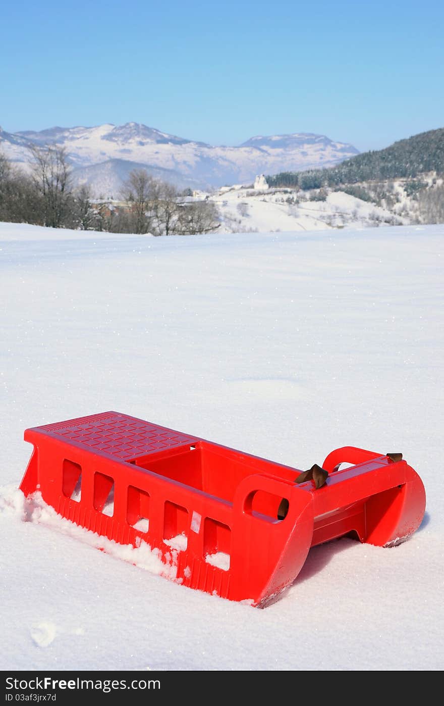 Plastic sledge with snow and mountine in background. Plastic sledge with snow and mountine in background