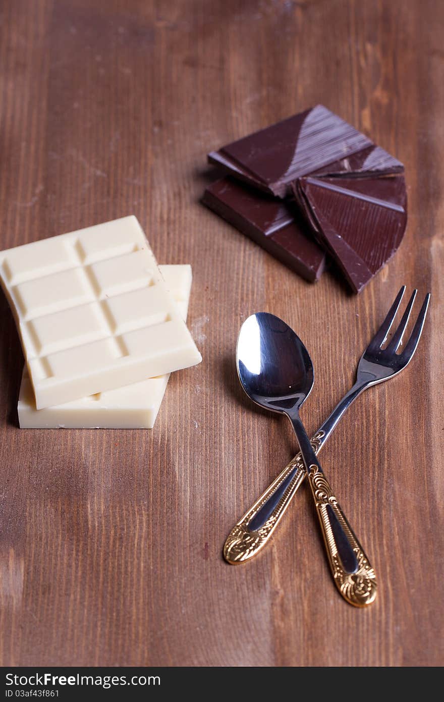 Chopped black and white chocolate with dessert service on wooden table. Chopped black and white chocolate with dessert service on wooden table