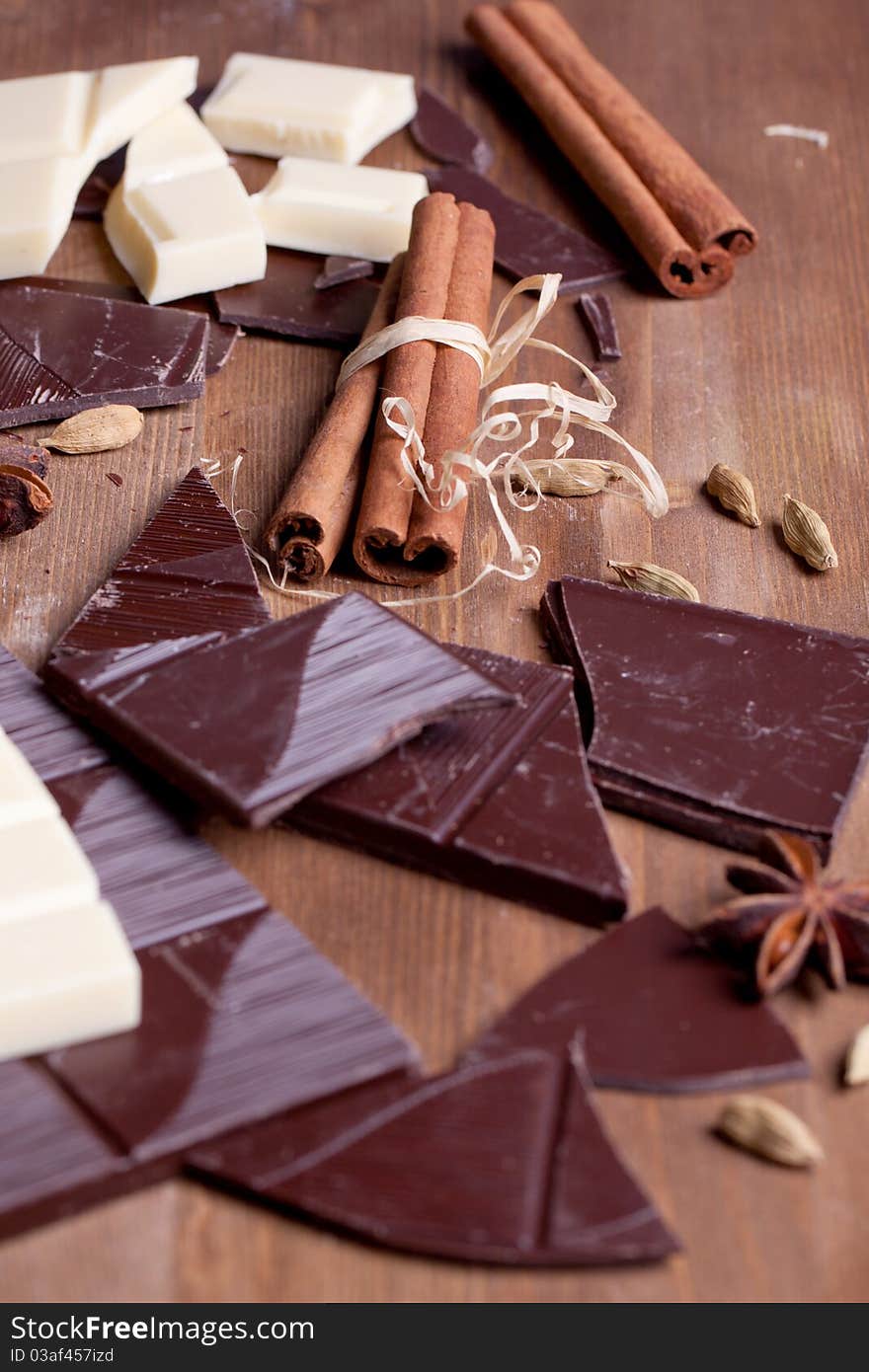 Chopped black and white chocolate with cinnamon, anise and cardamom on wooden table. Chopped black and white chocolate with cinnamon, anise and cardamom on wooden table