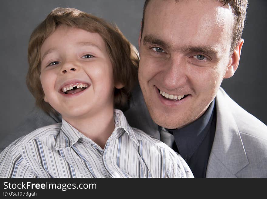 Father and son cheerfully talk. On a gray background. Boy not in focus.