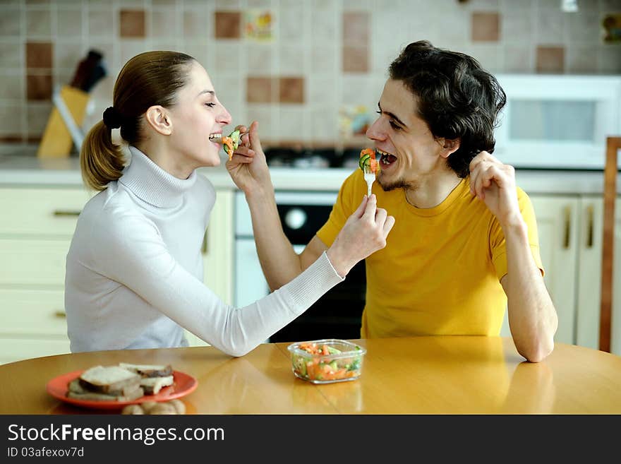 An image of young couple eating at kitchen. An image of young couple eating at kitchen