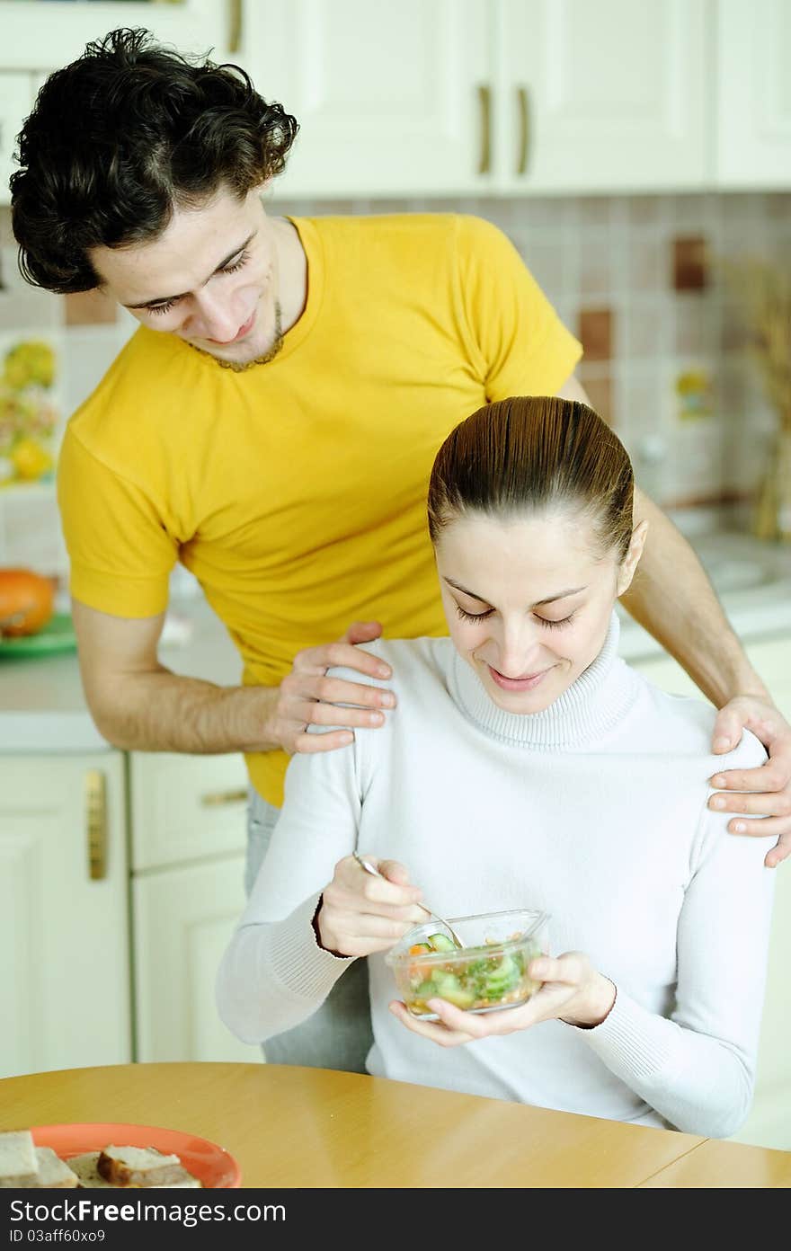 An image of young couple eating at kitchen. An image of young couple eating at kitchen