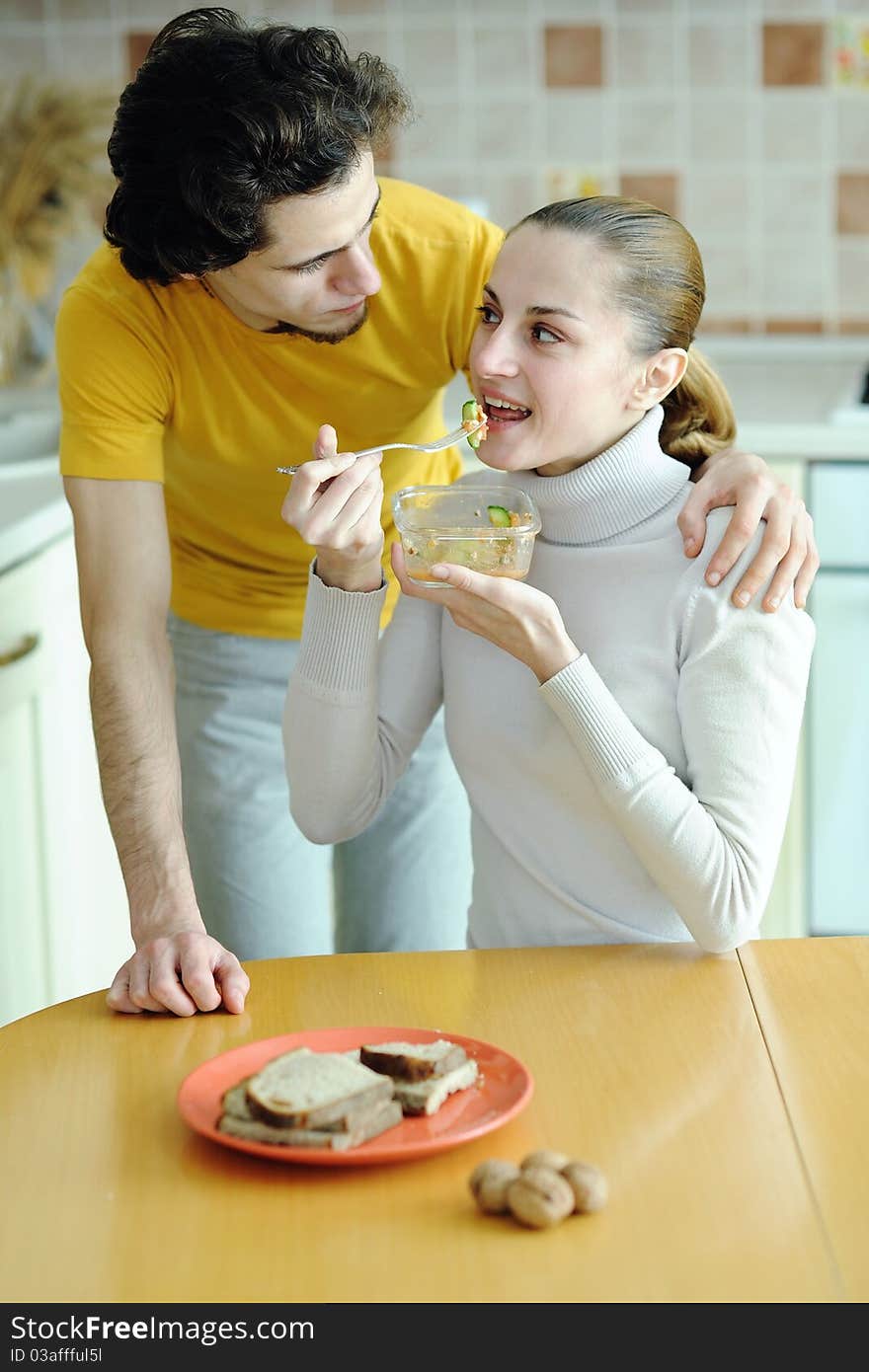 An image of young couple eating at kitchen. An image of young couple eating at kitchen