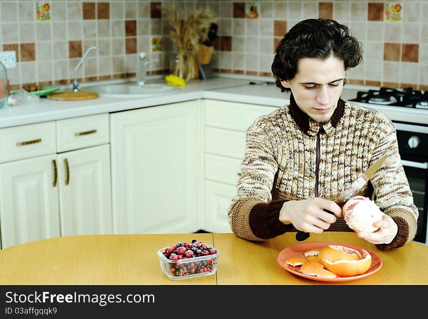 A man peelling the grapefruit in the kitchen