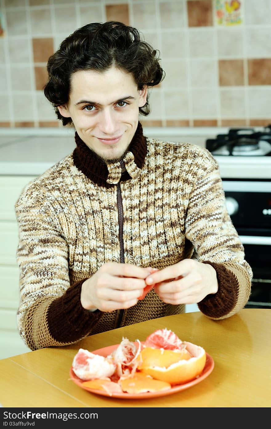 A man peelling the grapefruit in the kitchen