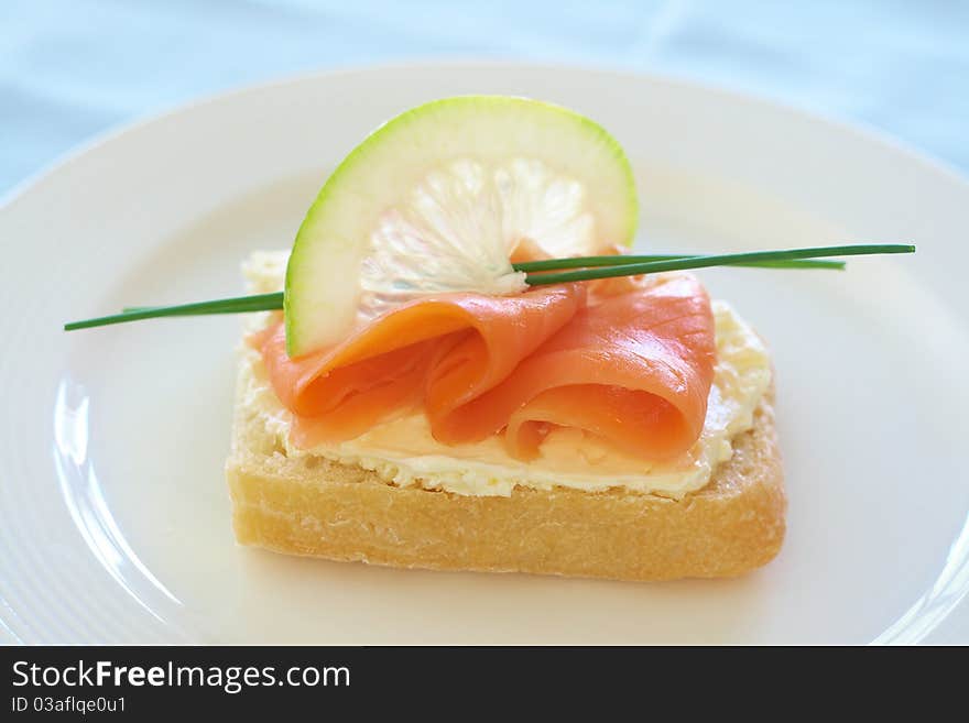 Smoked salmon and cream cheese on white bread with slice of lemon and chives