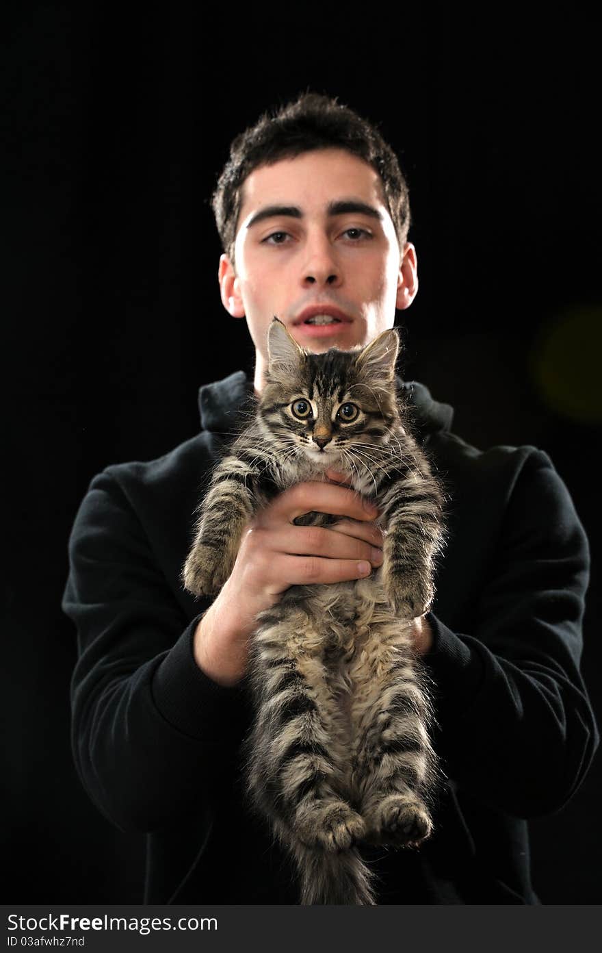 Young  handsome man holding little kitten on dark background. Young  handsome man holding little kitten on dark background