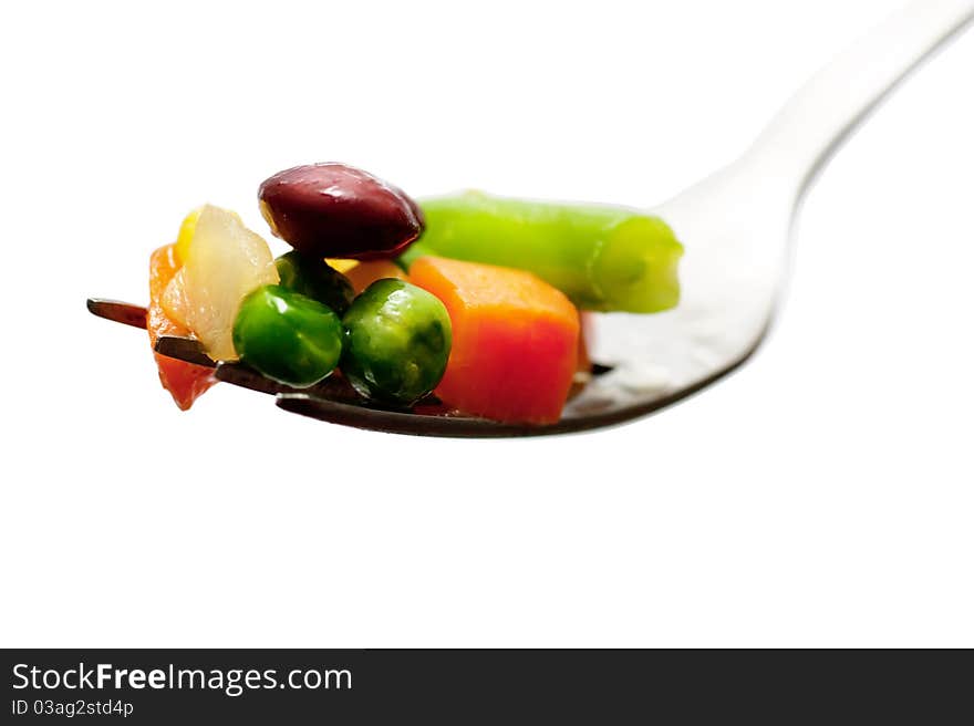 Pieces of boiled vegetables on a fork isolated over white