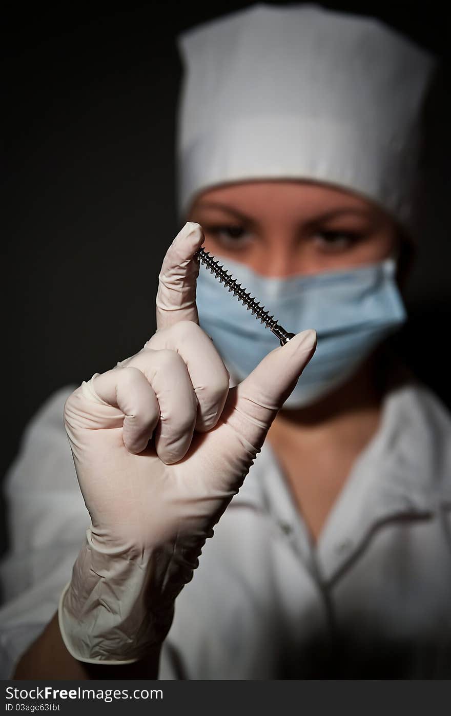 Young pretty surgeon holding nail for osteosynthesis close up