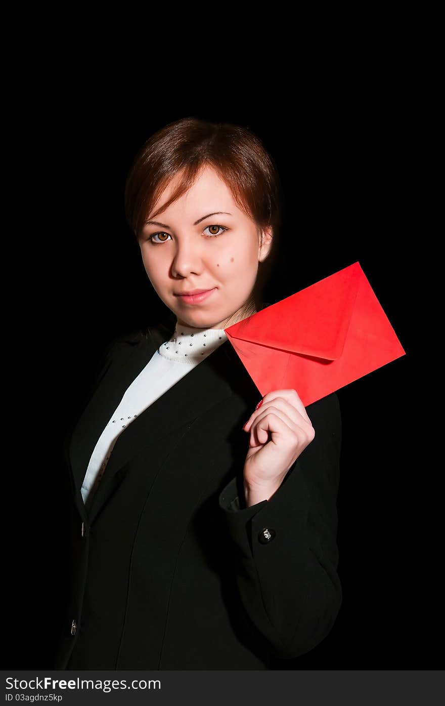 Pretty young business woman smiles and holds blank envelope isolated on black. Pretty young business woman smiles and holds blank envelope isolated on black