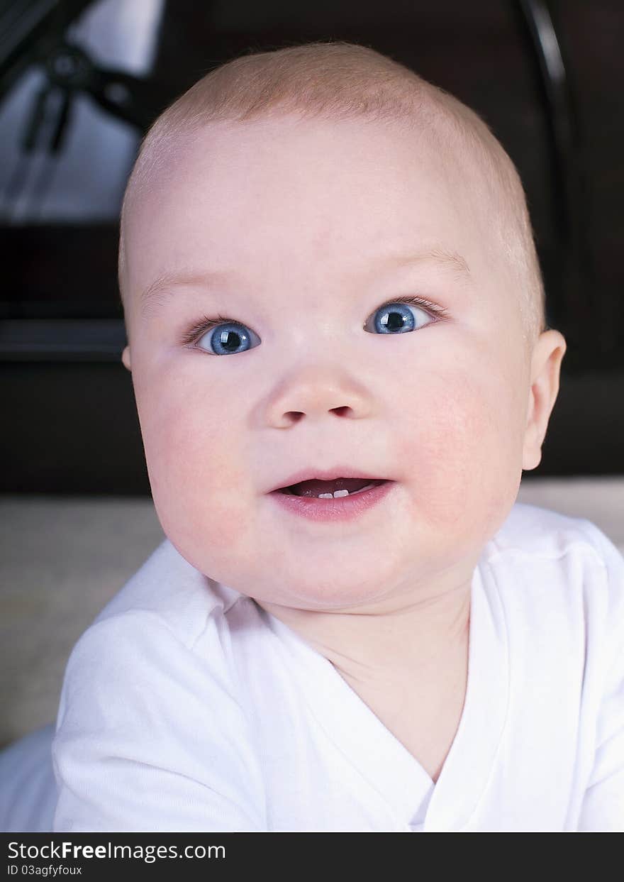 Baby with blue eyes, crawling on the big bed.