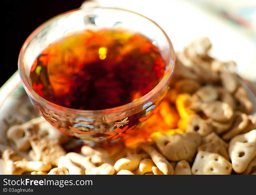 Closeup image of ceramic plate with crackers on it and a glass cup of tea. Closeup image of ceramic plate with crackers on it and a glass cup of tea