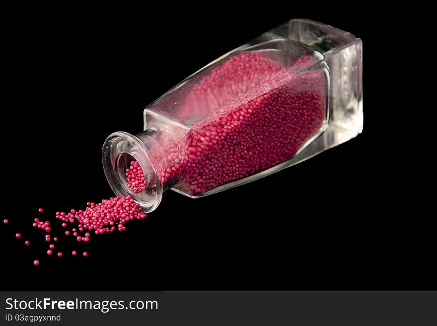 Pink Bath Pearls in Bottle isolated on Black Background. Pink Bath Pearls in Bottle isolated on Black Background