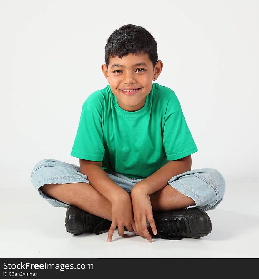 Young school boy, 10, sitting cross legged on the floor, wearing green t-shirt. Young school boy, 10, sitting cross legged on the floor, wearing green t-shirt.