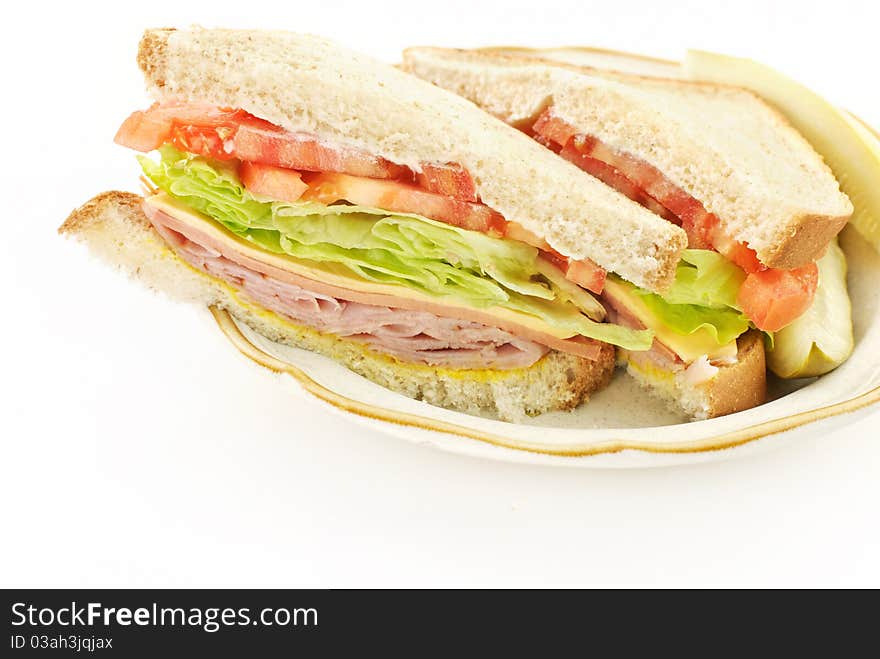 A delicious healthy ham, cheese and bologna sandwich, cut in half on a plate, white copy space. A delicious healthy ham, cheese and bologna sandwich, cut in half on a plate, white copy space