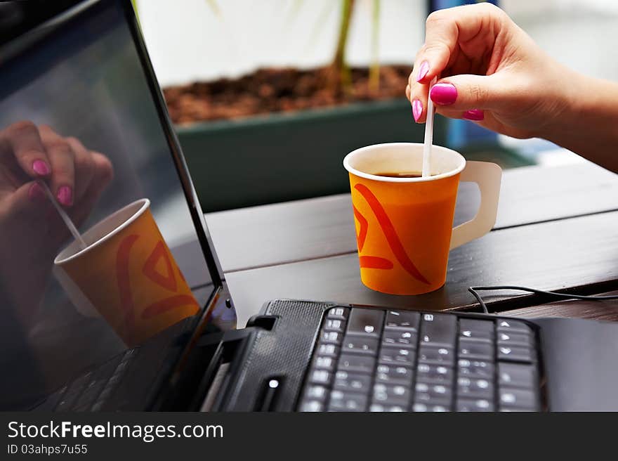 Paper cup of coffee on the table near the laptop on a business lunch