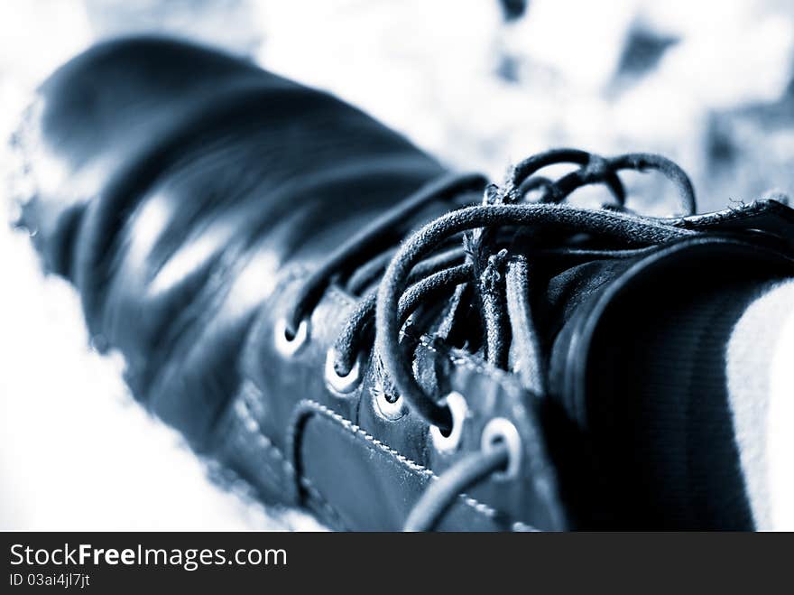 Blue toned image of an old men shoe with untied laces