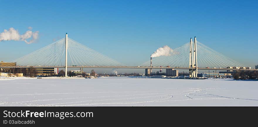 Big cable-stayed bridge across the frozen river in winter