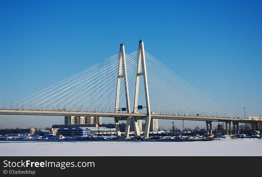 Big cable-stayed bridge across the frozen river in winter