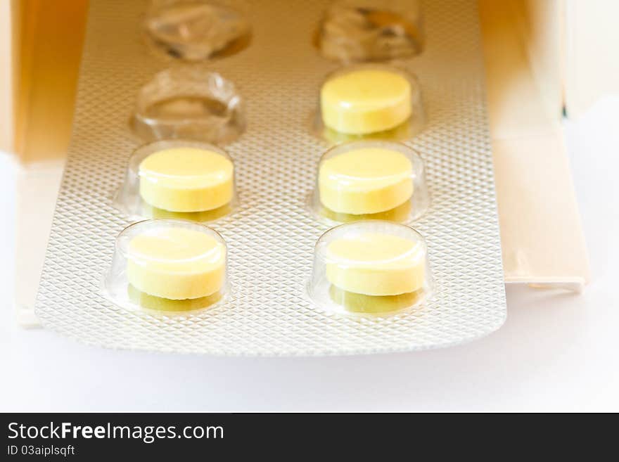 Yellow tablets in the packaging box is isolated on a white background. Yellow tablets in the packaging box is isolated on a white background