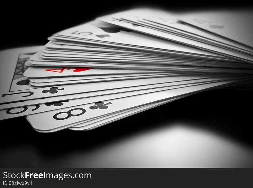 Close up on black and white deck of cards with only one card highlighted with red. Close up on black and white deck of cards with only one card highlighted with red