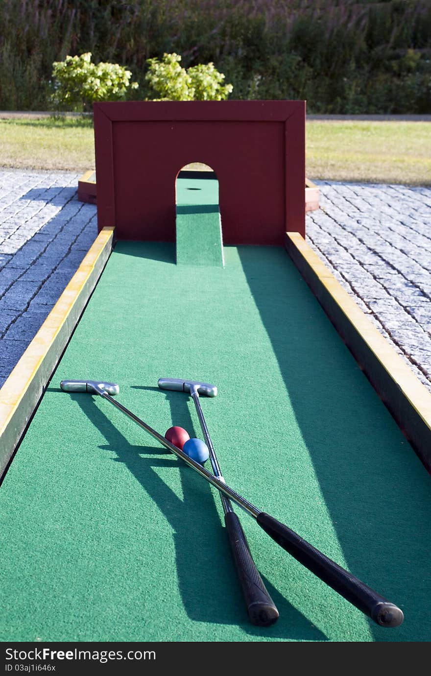 Set Of Mini Golf Clubs And Color Balls On Green