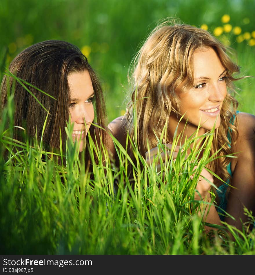 Girlfriends lays on green grass and smile. Girlfriends lays on green grass and smile