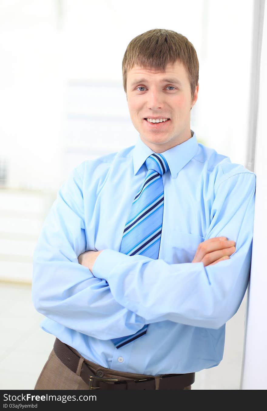 Portrait of a happy young business man leaning on the wall and looking at copyspace