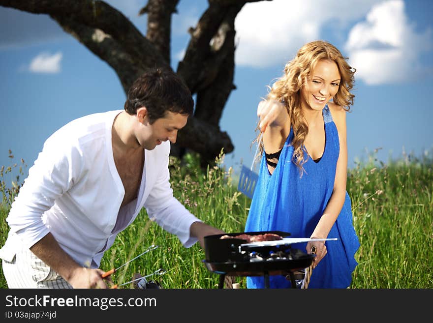 Lovers on picnic cook steak