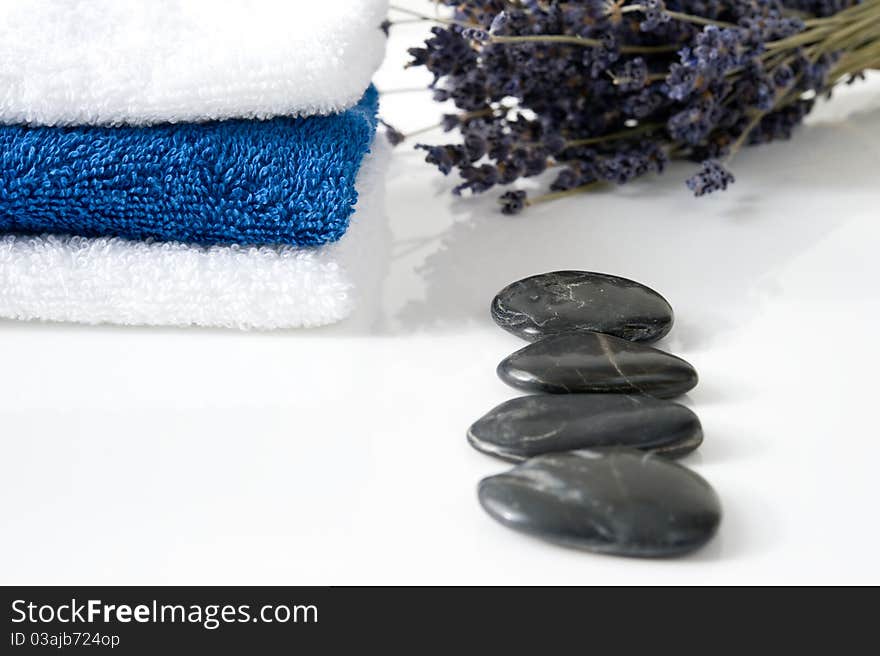 A tower of blue and white towels, stones and lavender on a white background. A tower of blue and white towels, stones and lavender on a white background